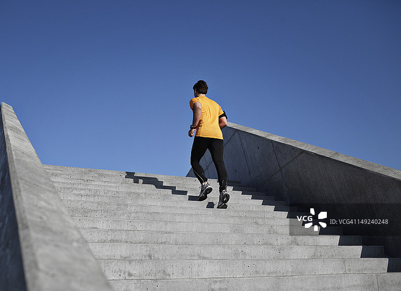 在城市环境中，男人跑上台阶。后视图片素材