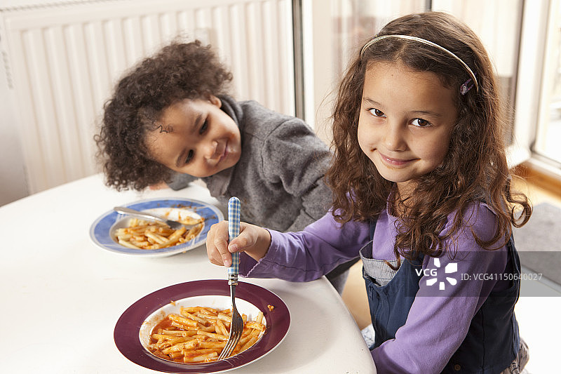 女孩们一起在餐桌上吃意大利面图片素材
