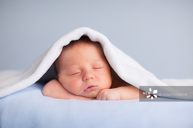 新生男婴在柔软的毯子下安静地睡觉图片素材