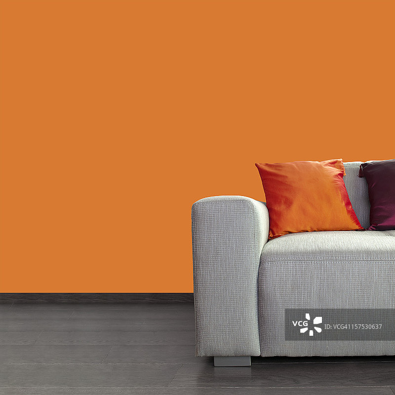 现代的灰色沙发和彩色枕头靠在橙色的墙壁上图片素材