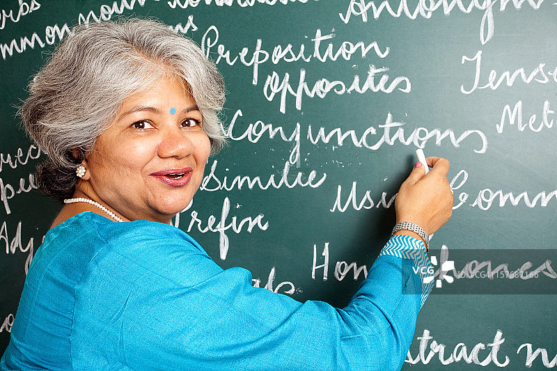 欢快的印度亚裔女英语老师在教室与greenboard图片素材