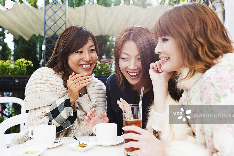 在阳光明媚的日子里，亚洲女人在街头咖啡馆的乐趣图片素材