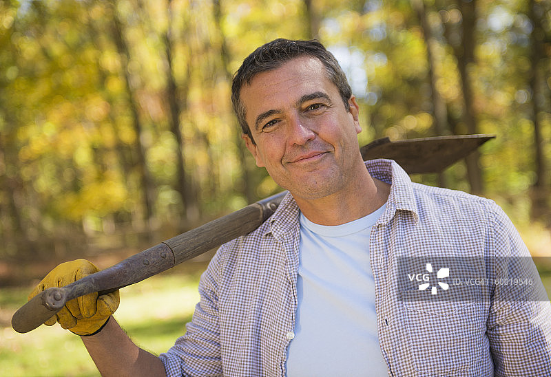一幅微笑的男人肩上扛着铲子的肖像图片素材