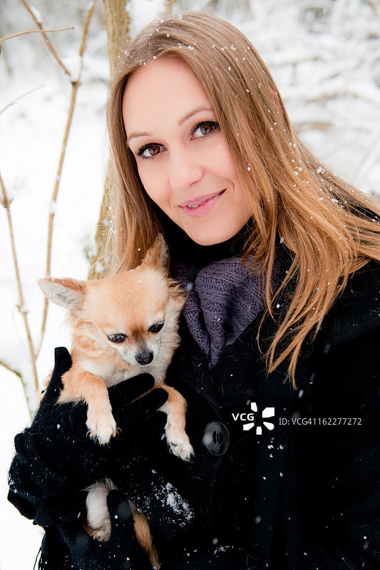 年轻女子和狗在雪中，肖像图片素材