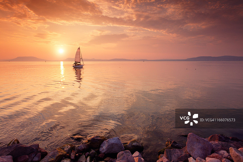 日落时湖面上的帆船。图片素材