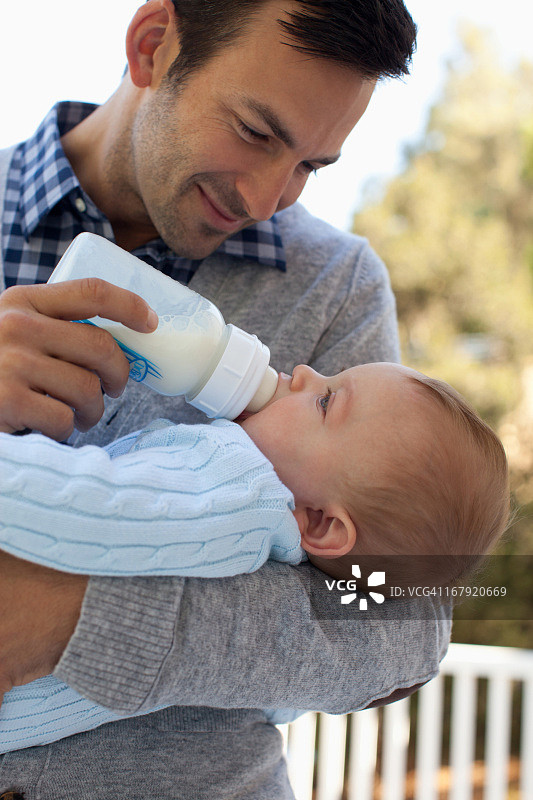 父亲在户外用奶瓶喂婴儿图片素材