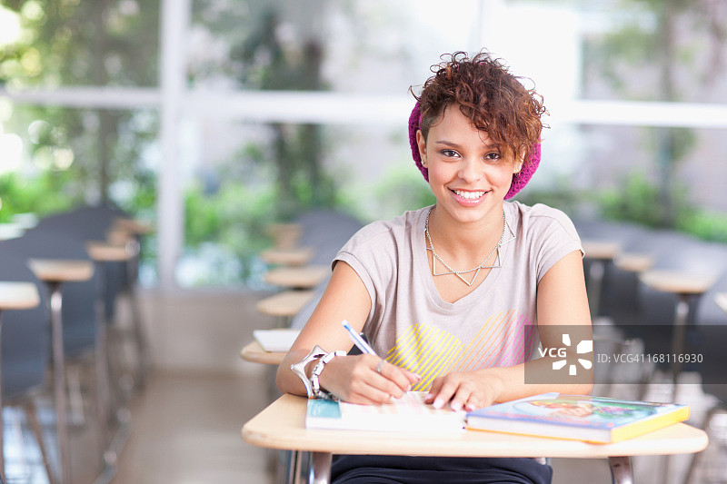 微笑的学生坐在书桌前图片素材