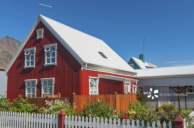 鲜艳的红色的房子，白色的尖桩篱笆，漂亮的花园图片素材
