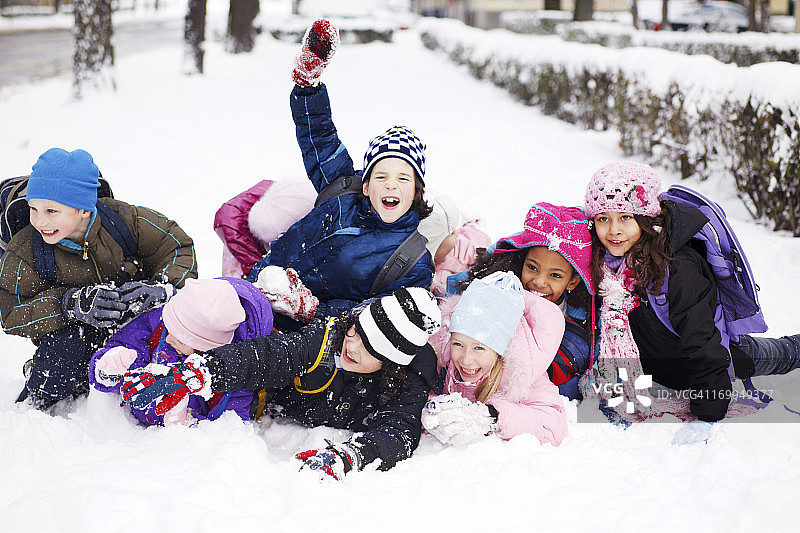 一群有趣的孩子躺在雪地里。图片素材