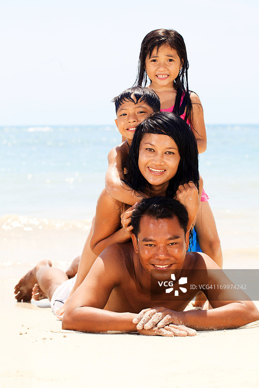 一个亚洲家庭在海滩上做金字塔。图片素材