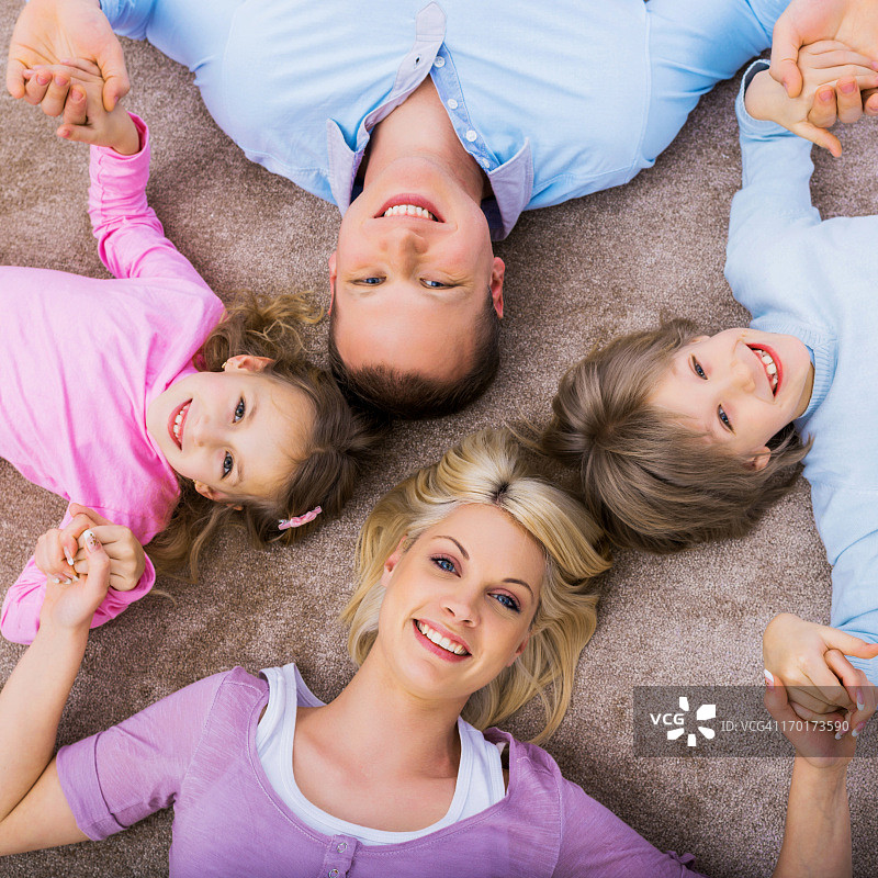 上图是一个年轻的家庭躺在地毯上图片素材