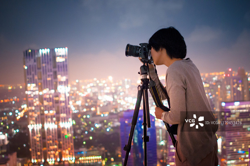 年轻的摄影师与大城市的夜晚灯光图片素材