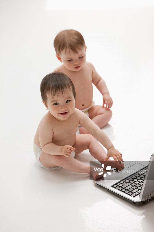 婴儿在地板上和笔记本电脑图片素材