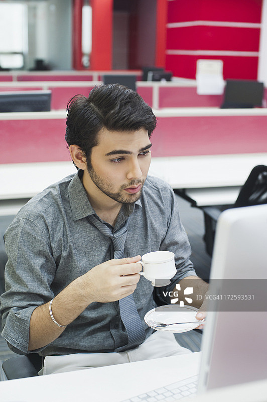 商人一边喝着咖啡一边看着电脑图片素材
