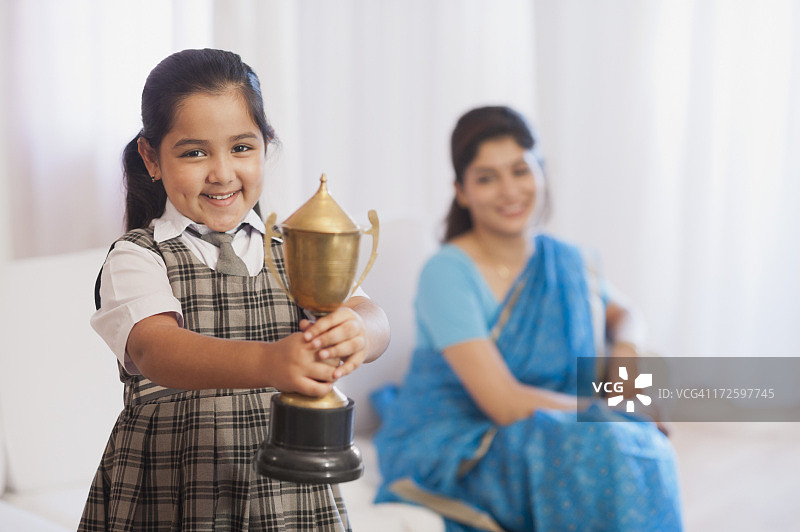 一个女孩的肖像展示她的奖杯和她的母亲在背景图片素材
