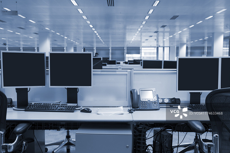 计算机屏幕在大型现代办公室室内，色调的形象图片素材