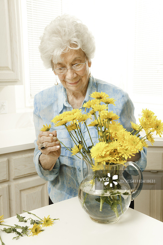有黄色切花的老妇人图片素材