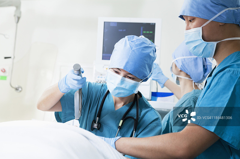 两个外科医生在手术台上工作，手里拿着手术设备图片素材