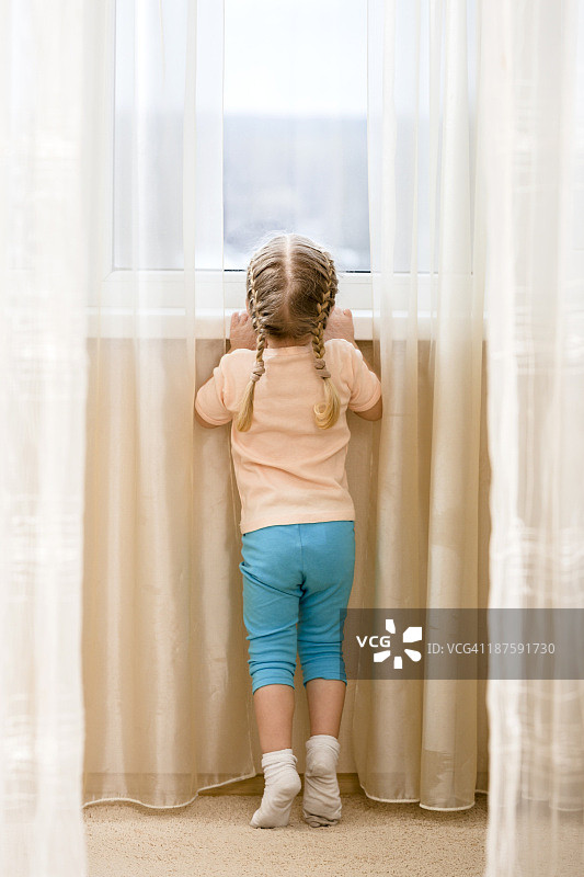 小女孩踮着脚尖想往窗外看图片素材