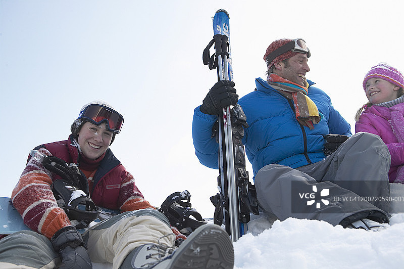 一家人坐在滑雪坡上，微笑着，画像图片素材