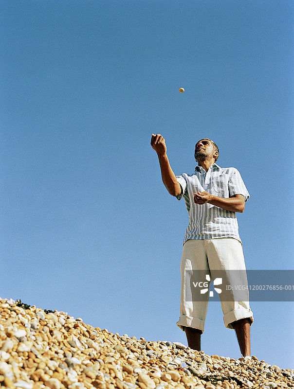 男人在沙滩上玩卵石，低角度的视角图片素材