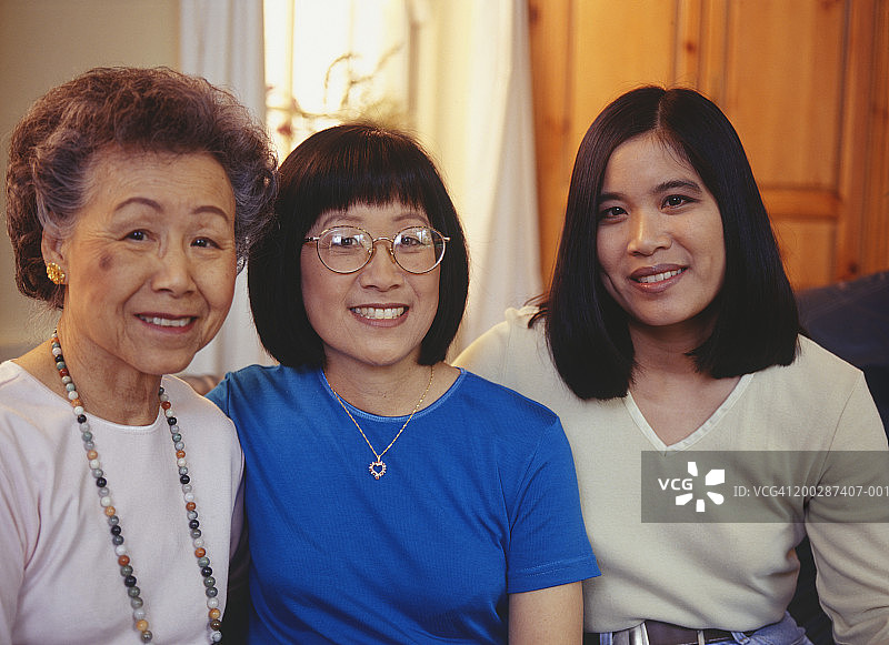 年长的母亲和两个女儿坐在沙发上的肖像图片素材
