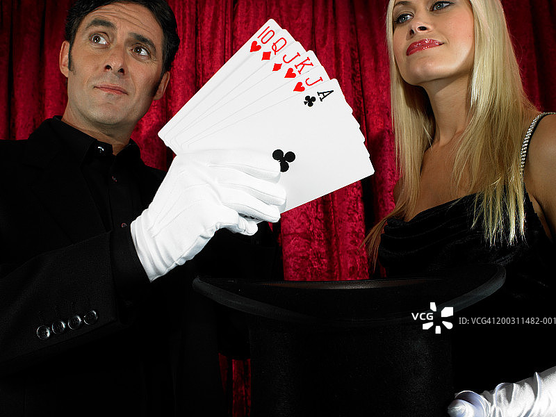 魔术师表演纸牌戏法与女助手图片素材