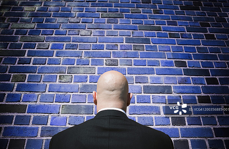 成熟的男人站在砖墙前，后视镜图片素材