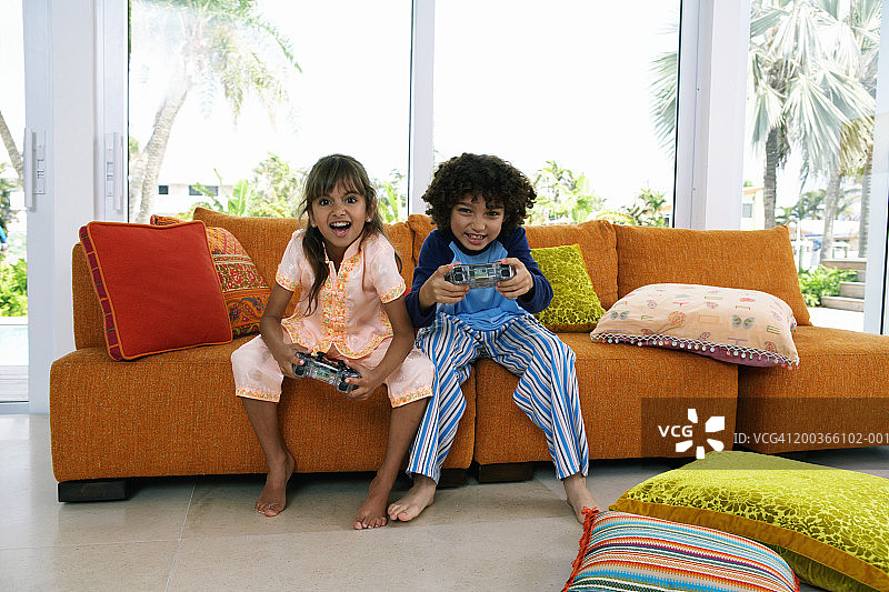 弟弟和妹妹(8-10)在玩电子游戏，微笑着，画像图片素材