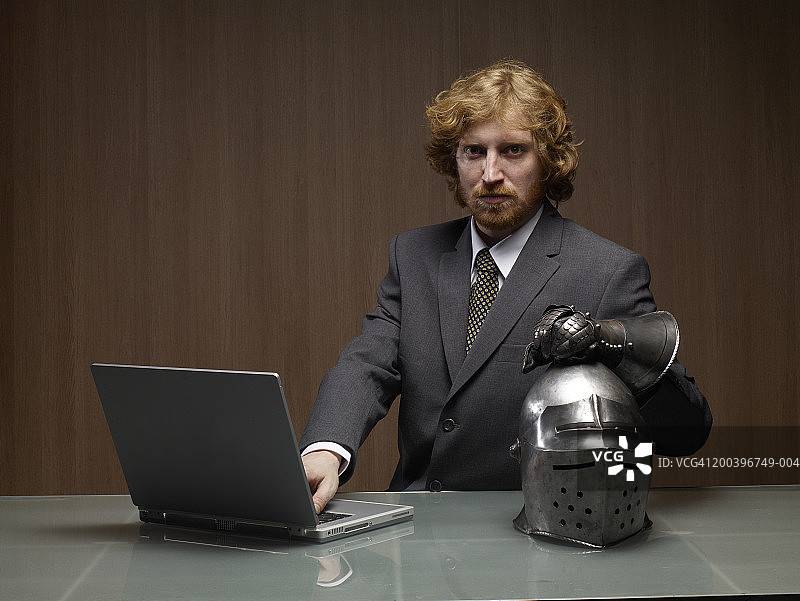 商人使用笔记本电脑由骑士头盔，肖像图片素材