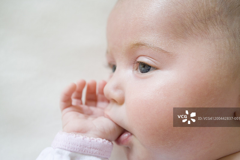 女婴(0-3个月)吸吮拇指，特写，侧视图(柔焦)图片素材