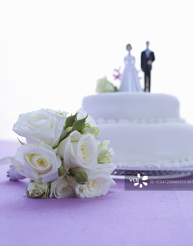 婚礼蛋糕，新娘和新郎在最上面，花束在前景图片素材