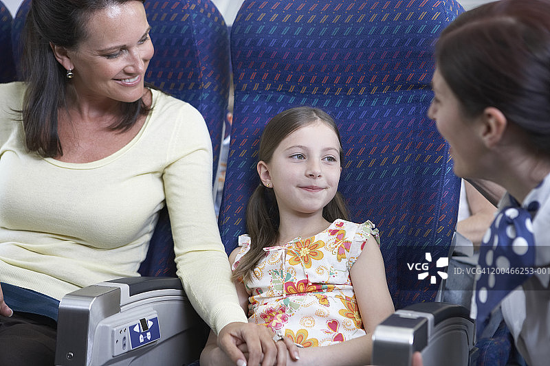 空乘人员在飞机上与女儿(6-8)交谈图片素材