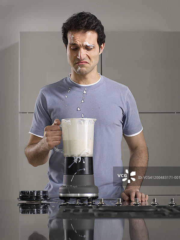 一名男子从厨房的搅拌机里倒了一杯奶昔图片素材