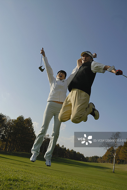 成熟的男人和女人在高尔夫球场上跳跃欢呼图片素材