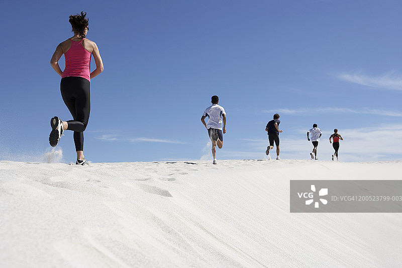 5个慢跑者(16-32)在沙丘上，后视图图片素材