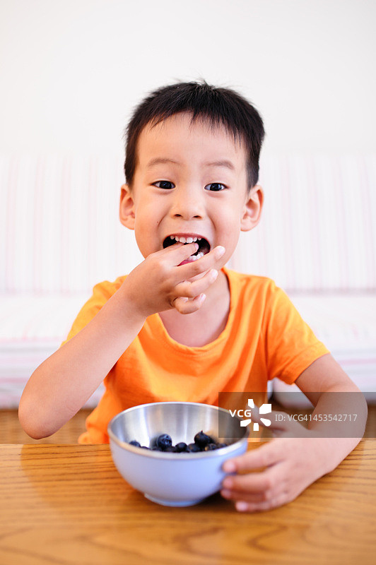 小男孩在吃蓝莓。图片素材