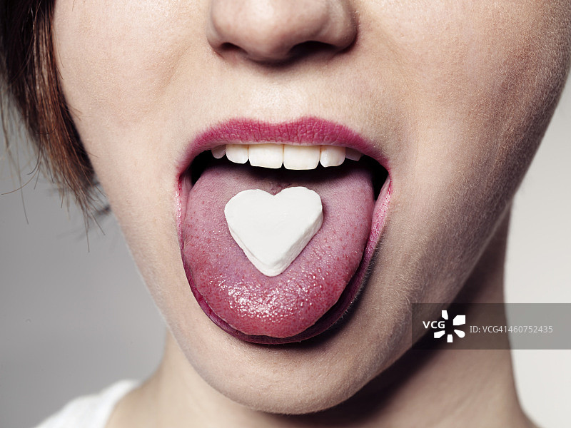舌头上有糖果心的年轻女子，靠近点图片素材
