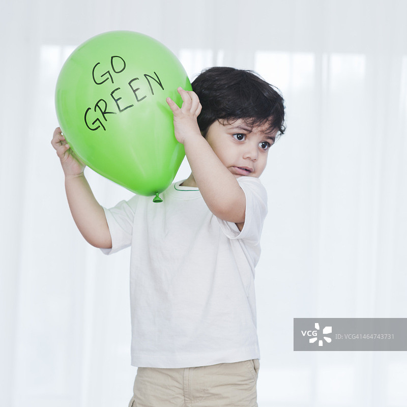 小男孩在玩一个绿色的气球图片素材