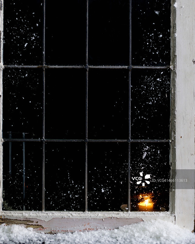 蜡烛燃烧在白雪覆盖的房子窗户图片素材