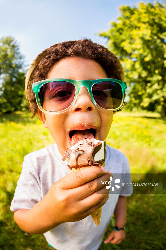 戴着太阳镜舔着巧克力冰淇淋的男孩图片素材