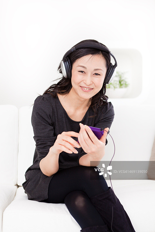 日本女性用手机和耳机听音乐图片素材
