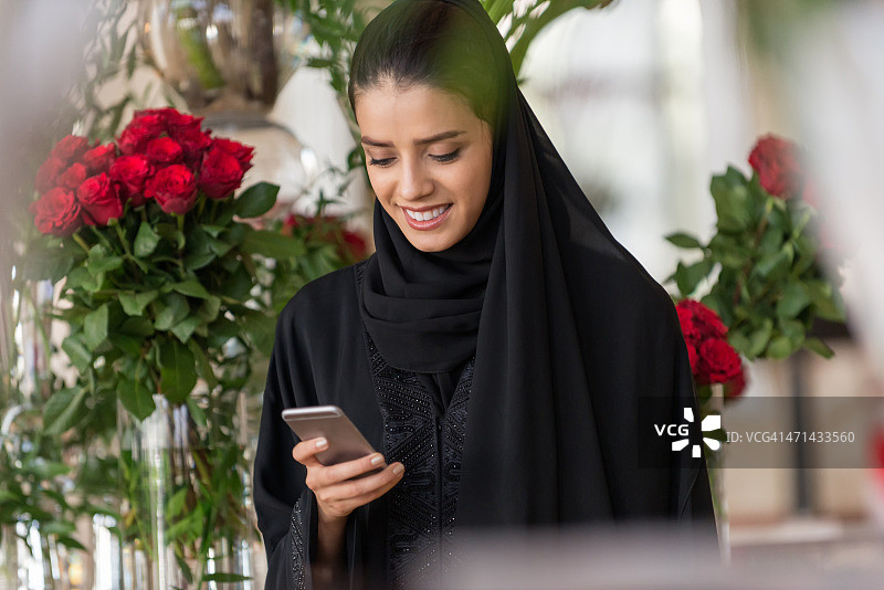 中东妇女被红玫瑰包围，正在读短信图片素材
