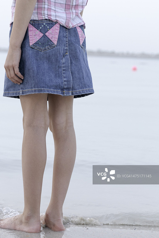 小女孩站在海滩的水边，地势很低图片素材
