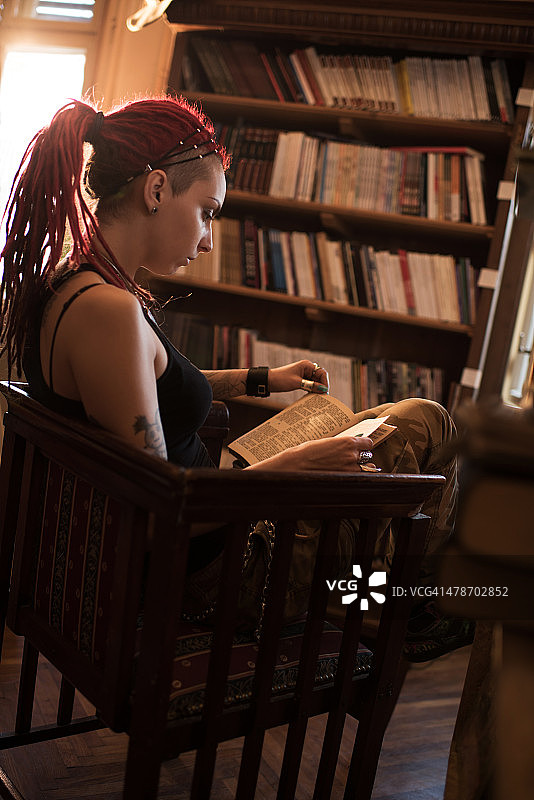 一个女人坐在图书馆里看书。图片素材