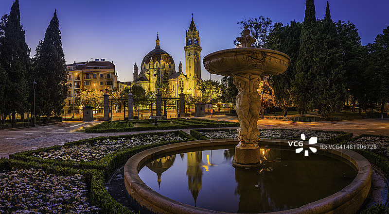 马德里雷蒂罗公园喷泉，华丽的教堂塔楼照亮了黄昏的西班牙图片素材
