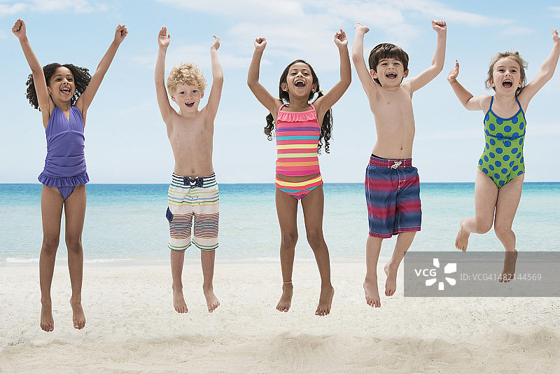 热情的孩子们在海滩上跳跃的肖像图片素材
