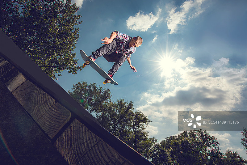 一个年轻人在户外玩滑板的低角度视图。图片素材