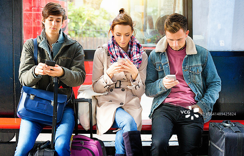 英国年轻人在等公交车时痴迷于手机图片素材