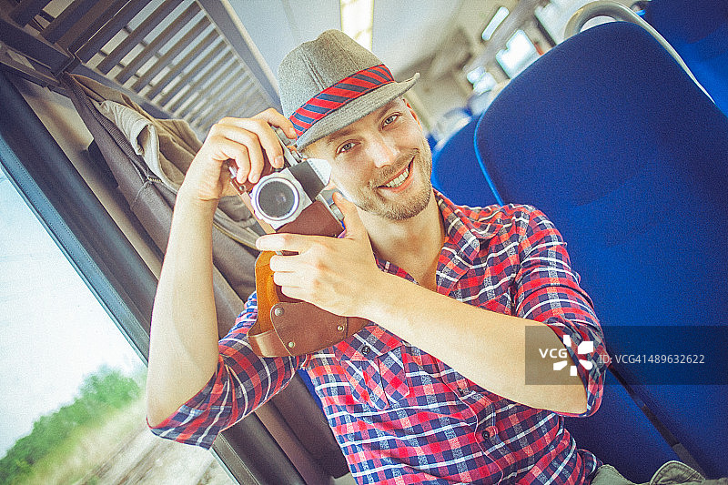 年轻人在火车上用复古相机拍照图片素材